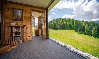A beautiful view from a modern wooden house onto a green meadow and forest. The large windows let in plenty of light and provide a relaxing atmosphere.
