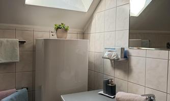 A modern bathroom with a sink and a large window. The walls are tiled and there are towels in soft colors.