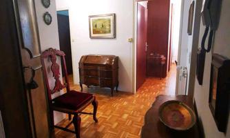 A beautiful hallway with a wooden floor and classic furniture. Pictures and decorative items hang on the walls.