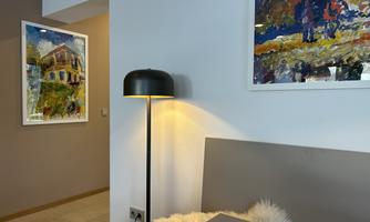 A stylish room with a modern lamp and a cozy atmosphere.  
Two colorful pictures hang on the wall, giving the room character.