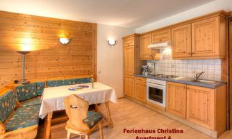 A cozy kitchen with wooden furniture and a dining area. The room is bright and has a friendly design.