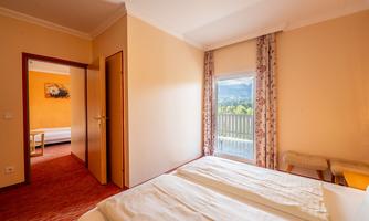 A cozy bedroom with two beds and a window that offers a view of the mountains. The walls are painted in soft colors, and the decor is simple and inviting.