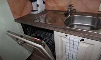 A modern kitchen with a sink and a dishwasher. The dishwasher is open and shows empty compartments.