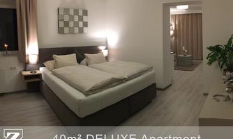 A modern deluxe apartment with a large double bed and stylish furnishings. Soft lighting and warm colors create a cozy atmosphere.