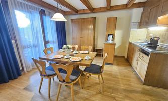 A cozy kitchen with a dining table and six chairs. The table is beautifully set, and the wooden ceiling gives the room a warm atmosphere.