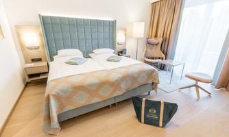 A modern hotel room with two beds and stylish furnishings. Large windows let in plenty of light and create an inviting atmosphere.