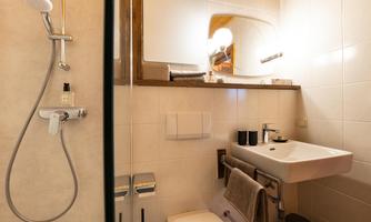 A modern bathroom with a shower and sink. It is bright and well-equipped with skincare products.