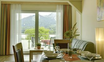 A cozy living room with a view of the mountains. The table is set and large windows provide plenty of daylight.
