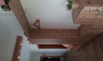 An inviting hallway with wooden paneling and a hanging cabinet. A small plant and decoration give the room a cozy atmosphere.