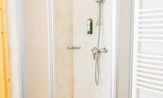 A modern shower with glass walls and a simple design. The walls are in light, neutral colors.