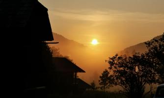 A beautiful sunrise behind the mountains. Gentle wisps of fog surround the landscape.