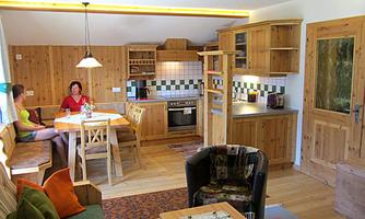 A cozy wooden apartment with a modern kitchen and a dining area. Two people are sitting at the table enjoying the relaxed atmosphere.
