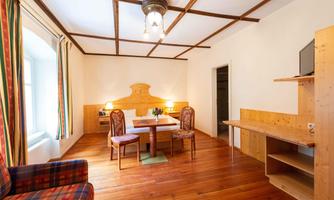 A cozy room view with wooden floor. There is a table with chairs and a small seating area.