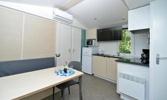 A modern kitchen with a small dining area. The room is bright and friendly, with a window that allows a view outside.