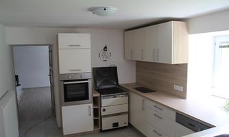 A modern kitchen with bright cabinets and a cooking surface. The room is well-lit and has an open layout.