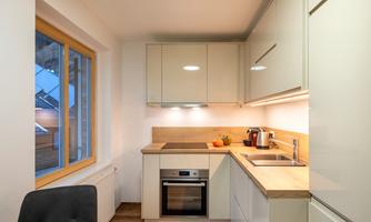 A modern kitchen with light cabinets and a wooden countertop. The room has a window and is well-lit.