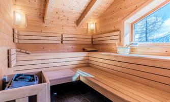 A cozy interior of a wooden sauna. The light and the windows provide a view of the nature outside.