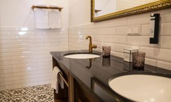 A modern bathroom with two sinks and an elegant mirror. The tiles have a beautiful, decorative pattern.