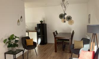 A modern apartment with a dining area and cozy seating. The room is bright and cheerfully decorated, with plants and decorative elements.