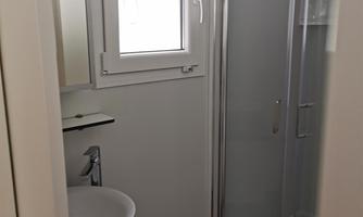 A modern bathroom with a shower and sink. Bright and cheerful thanks to a window.