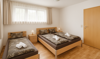 A bright bedroom with two single beds and a large window. The bedding is kept neutral and fresh towels are laid out on the beds.