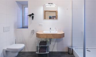 A modern bathroom with a minimalist design. It includes a sink, a toilet, and a shower.