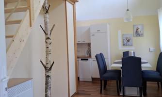 A bright living kitchen with a wooden staircase and a stylish rug. A decorative log gives the room a special touch.