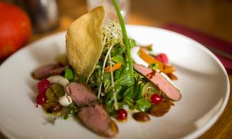 A beautifully arranged salad with tender meat, fresh vegetables, and a crispy decoration. The colors are vibrant and appealing.