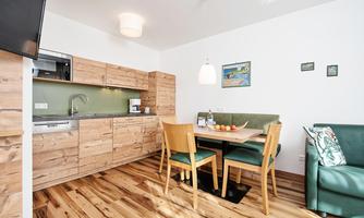 A modern kitchen with wooden cabinets and a dining area. The room is bright and invitingly designed.