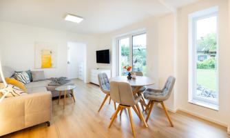 A modern living room with a comfortable sofa and a table. Large windows provide plenty of natural light.