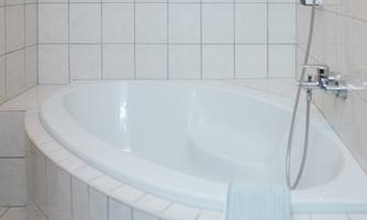 An elegant bathroom with a modern, round bathtub. White tiles and a bright atmosphere create a clean, relaxing ambiance.