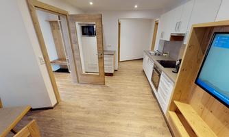 A modern apartment with an open kitchen and bright wooden furniture. The space feels friendly and inviting.