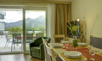 A cozy dining area with a table and chairs. Through the window, you can see mountains and a terrace.