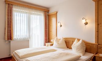 A cozy bedroom with two single beds and bright curtains. The walls are made of wood, and the room has a warm, inviting atmosphere.