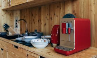 A modern kitchen with a red coffee maker and dishes. Wooden shelves and a sink complement the cozy atmosphere.