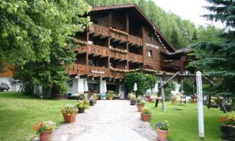 A traditional wooden building with several balconies and a beautiful garden. Colorful flowers in pots give the entrance an inviting atmosphere.