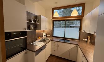 Modern white kitchen with induction stove, oven, and dishwasher.