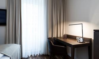 A modern room with a desk and a comfortable chair.  
Plenty of daylight streams through the curtains, creating an inviting atmosphere.