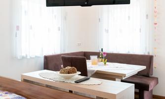 A modern room with a cozy bed and a large television. The dining area is bright and inviting, with a table and seating area.