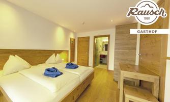 A modern room with two single beds, wood paneling, and blue towels. In the background, the bathroom is visible, and the logo of the Gasthof Rausch is in the upper right corner.