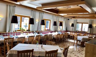 An inviting restaurant with wooden tables and chairs. The room is brightly lit and has a cozy atmosphere.