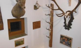 A rustic wall with hunting trophies and wooden embellishments. Some pictures and a cross are also visible.