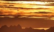 A breathtaking mountain landscape at sunset. The sky displays warm colors and silhouetted peaks.