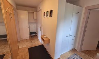 An inviting hallway with a wardrobe and light walls. A carpet and a small table create a cozy atmosphere.