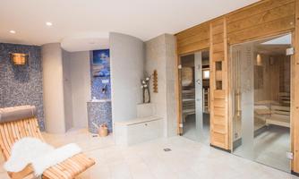 A relaxing wellness room with a sauna and cozy loungers. The walls are designed in calming colors.