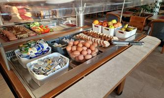 A buffet with various foods, including fresh eggs, fruit, and a selection of sauces. The image shows a neat and inviting presentation of the dishes.