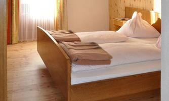 A cozy bedroom with a double bed and wooden floor. Large windows let in plenty of light and create an inviting atmosphere.