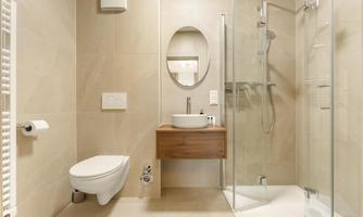 A modern bathroom with a shower, a sink, and a toilet. The walls are kept in light, neutral colors.