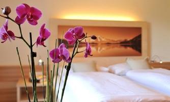 An elegant bedroom with two beds and soft colors. In the foreground, purple orchids bloom.