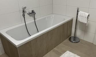 A modern bathroom with a white bathtub and a stylish towel holder. The floor is designed with large tiles in neutral colors.